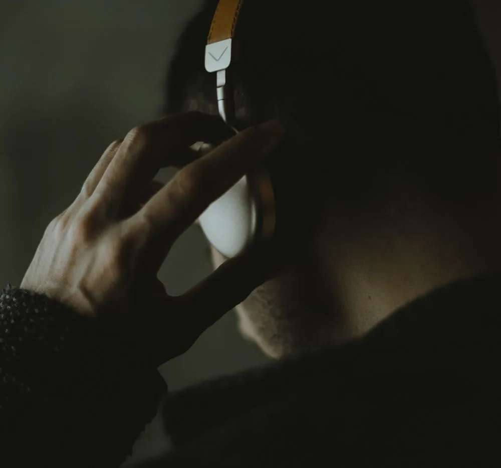 Close-up of a listener holding a headphone earcup