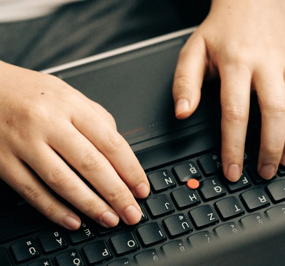 Hands typing on a laptop keyboard