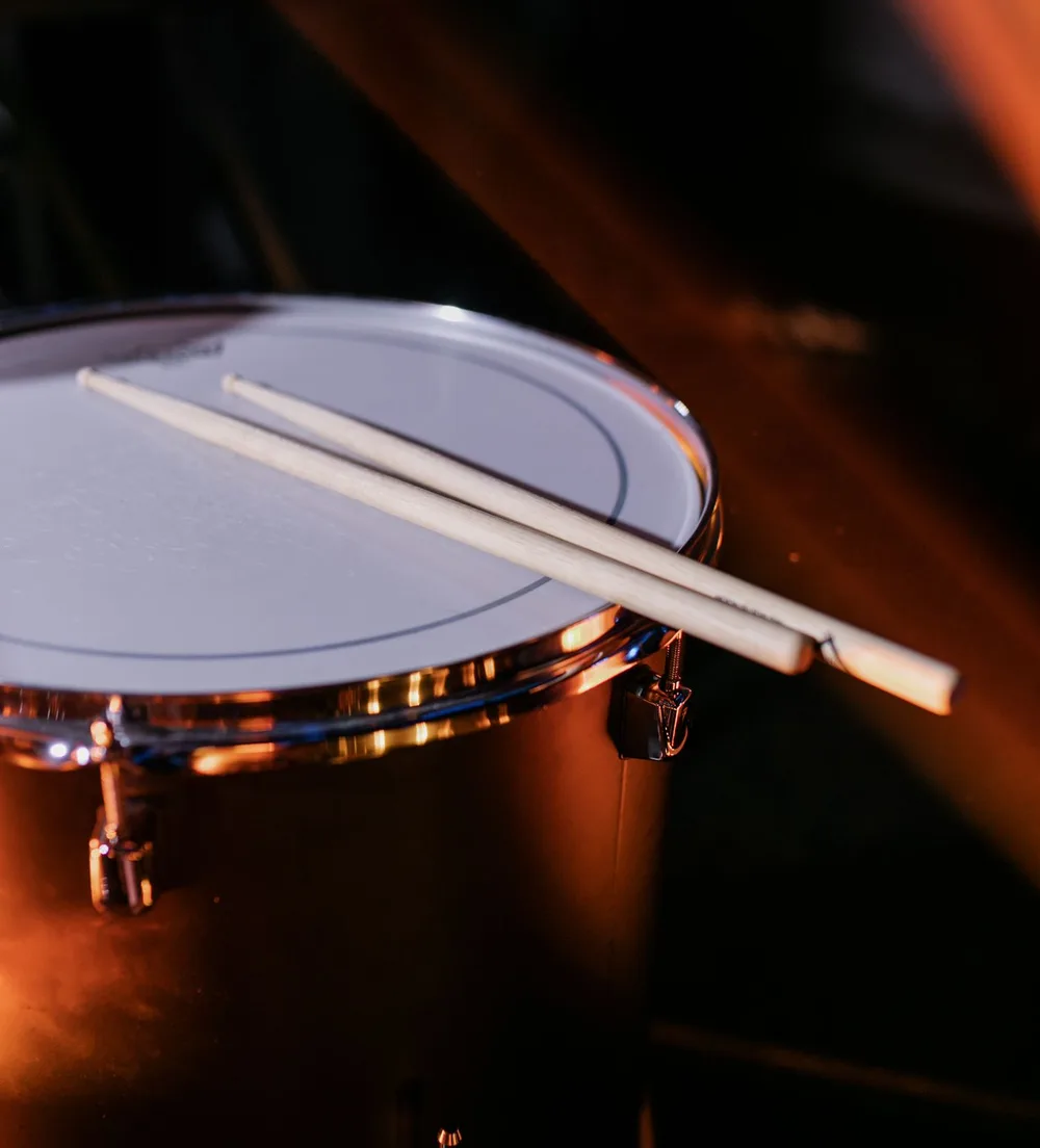 Wooden drumsticks resting across a snare drum